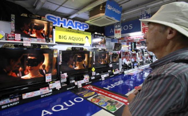 A man looks at Sharp Corp's Aquos TVs in a Tokyo shop in this August 8, 2012 file photograph. REUTERS/Yuriko Nakao