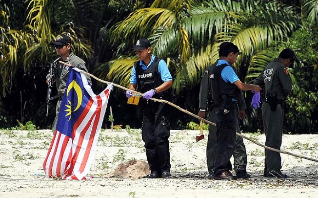 Thai police officers take down a Malaysian flag hoisted in protest by militants in the southern province of Narathiwat on Friday. Photo: AFP