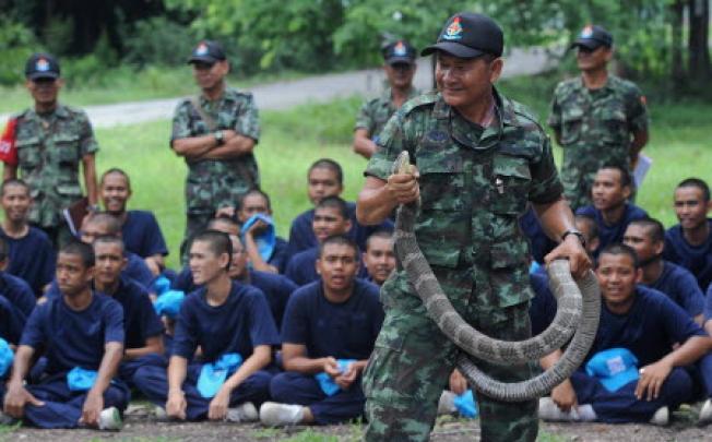 A Thai soldier holds a cobra as teenage students take part in Thai army bootcamp training at a military camp in Lopburi province. Photo: AFP.