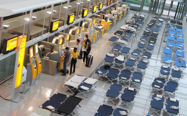 Flight passengers stand at the Lufthansa check-in in front of camp beds at the Franz-Josef-Strauss airport in Munich, on Wednesday. Photo: AFP 