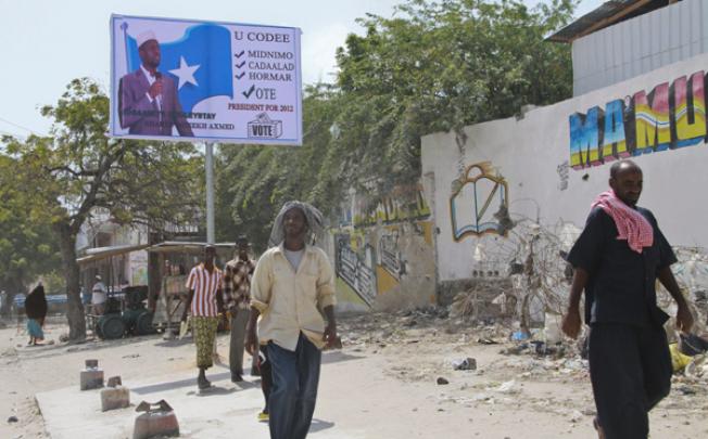 Pedestrians walk past a campaign billboard of incumbent president Sharif Sheikh Ahmed in the capital Mogadishu on Sunday. Photo: EPA