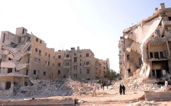 People walk past a row of destroyed buildings near the Al-Hayat Hospital in the northern Syrian city of Aleppo on Monday. Photo: AFP