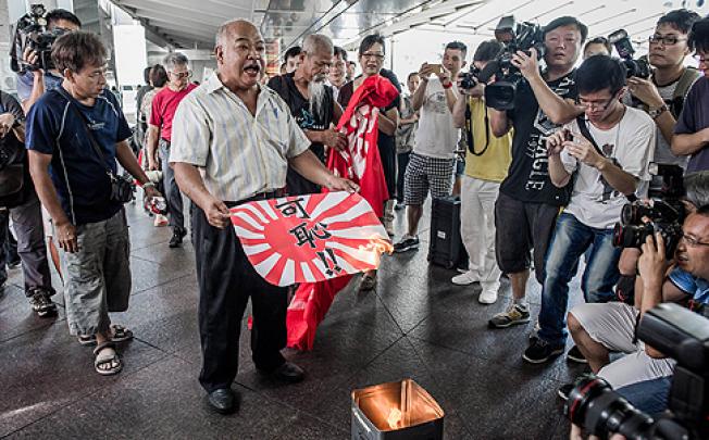 Activist Tsang Kin-shing burns a paper Japanese imperial military flag outside the consulate in Central, Hong Kong, on Wednesday. Photo: AFP