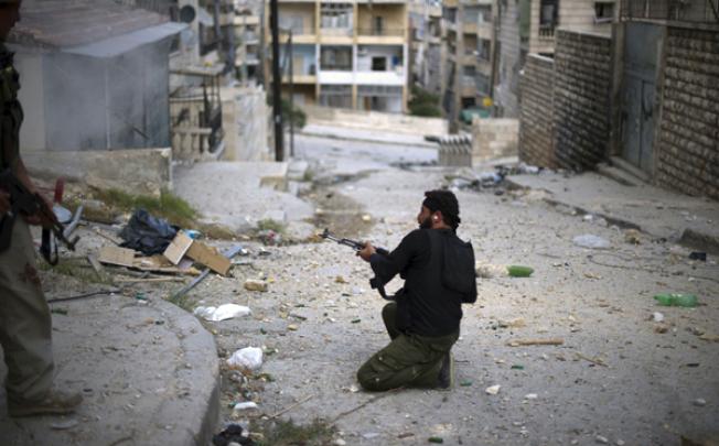 A fighter with the Free Syria Army (FSA) fires his weapon during skirmishes with regime forces in the contested neighborhood of Izza in the northern city of Aleppo on Tuesday. Photo: AFP 