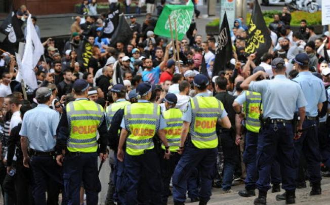 Police watch protesters near the US Consulate General in central Sydney on Saturday, as a wave of unrest against a film that mocks Islam spread to Australia, bringing hundreds out to demonstrate. Photo: AFP