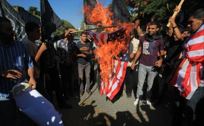 Palestinian men burn the US flag during a demonstration against a film deemed offensive to Islam, on September 12, 2012  in front of the United Nations headquarters in Gaza City.  Photo: AFP