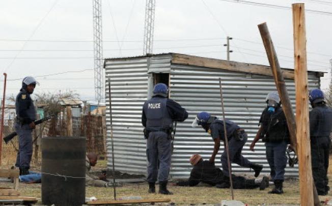 Police officers round up a group of men as they patrol the area near the Lonmin Platinum Mine near Rustenburg, South Africa, Saturday. Photo: AP