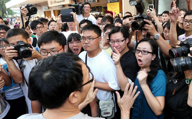 A supporter of the cross-border traders tries to placate angry local protesters outside Sheung Shui station yesterday. Photo: David Wong