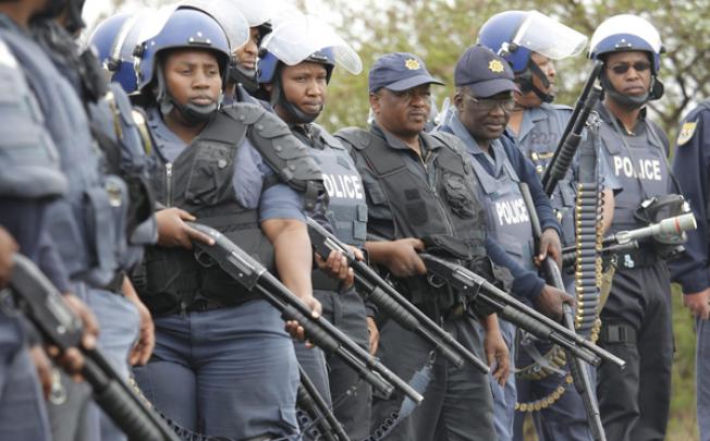 South African police block a main road to prevent un-armed miners from the Anglo Platinum Mine from reaching the police station in Rustenburg on Sunday. Photo: EPA