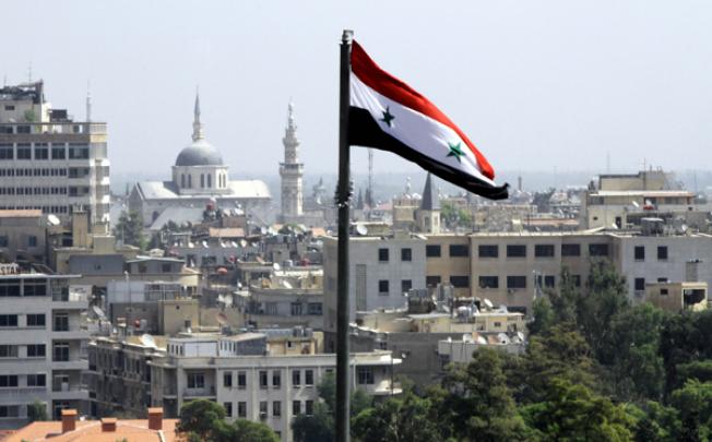 The Syrian flag flutters above Damascus on Thursday. Photo: AFP