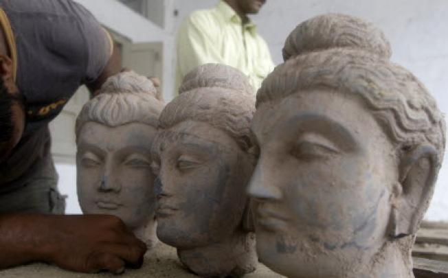 A Pakistani official looks at Buddha statues confiscated by custom authorities in Karachi. Pakistan is struggling to stem the flow of ancient Buddhist artifacts smuggled to collectors around the world. Photo: AFP