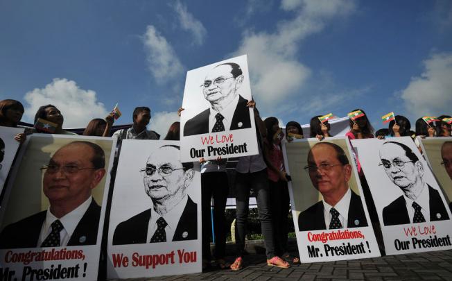 Supporters hold pictures of Myanmar president Thein Sein as they welcome him at Yangon International Airport. Photo: AFP  