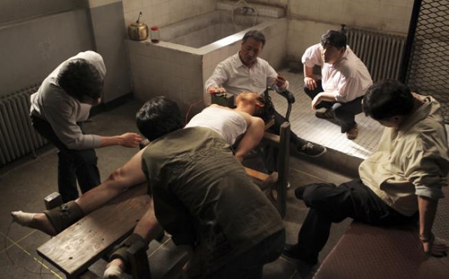 South Korean actor Lee Kyeong-yeong, third from right on a chair, acts as a torturer in a scene from the film <i>National Security</i>. Photo: AP