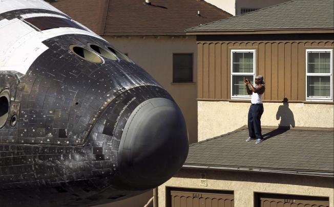 A man photographs Endeavour as it passes by. Photo: Reuters