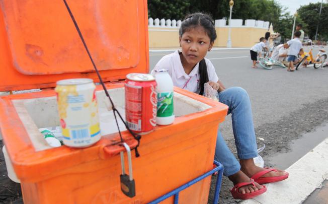 A young Cambodian girl sells drinks by a road in Phnom Penh. Photo: EPA