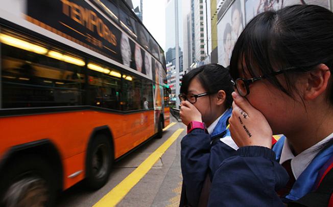 Students cover their faces to avoid traffic fumes in Causeway Bay. Photo: Nora Tam