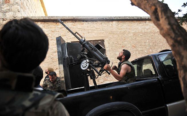 A rebel fighter fires an anti-aircraft gun as a Syrian army helicopter flies overhead in Maarat al-Numan. Photo: AFP