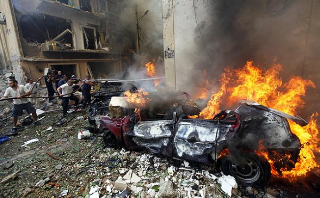 Firefighters extinguish burning cars after an explosion in Achrafiyeh, Beirut. Photo: AP