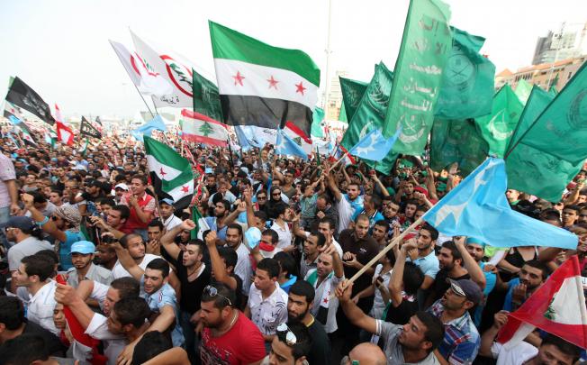 Lebanese protestes wave Syrian revolutionary flags, national flags and Islamic flags as they gather in Martyrs' Square for the funeral of General Wissam al-Hassan in Beirut. Photo: AP