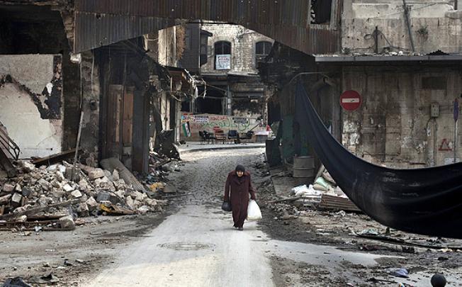 An Syrian woman crosses a street next to a black cloth used to separate the area from Syrian government forces' snipers fire in Aleppo. Photo: AFP