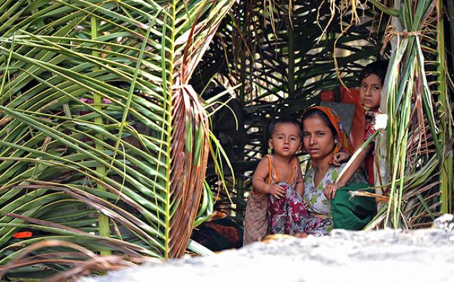 A Muslim Rohingya woman sits with her children in her temporary shelter at a village in Minpyar in Rakhine state. Photo: AFP