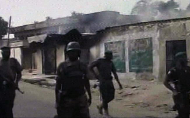 Nigerian soldiers walk past burnt out houses in Maiduguri on October 8. Photo: AP