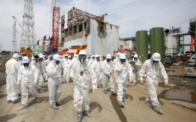 Tepco employees in front of the No. 4 reactor building at the company's Fukushima Dai-Ichi nuclear power plant in Okuma Town, Fukushima Prefecture, Japan. Photo: EPA