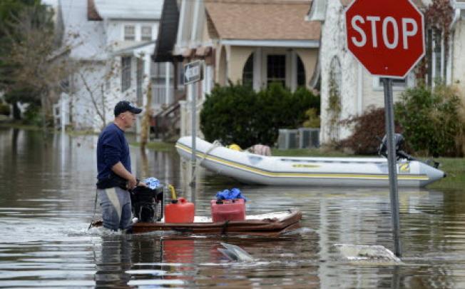 New Jersey resident Ray Bowman uses a floating hot tub cover to transport a generator and petrol down a street heavily flooded by Hurricane Sandy, in Belmar on Thursday. Photo: EPA 