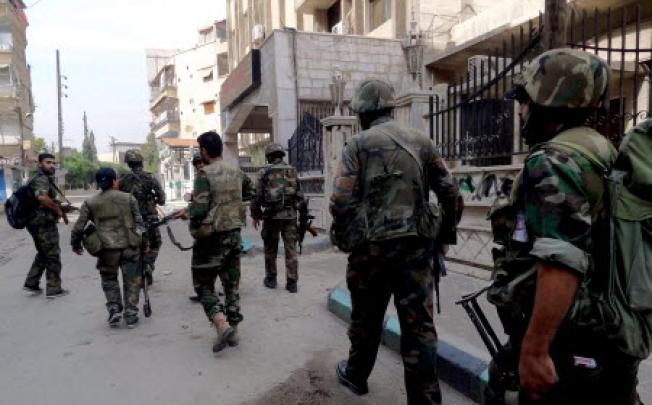 Syrian soldiers patrolling the street in Harasta area eastern Damascus on Thursday. Photo: EPA