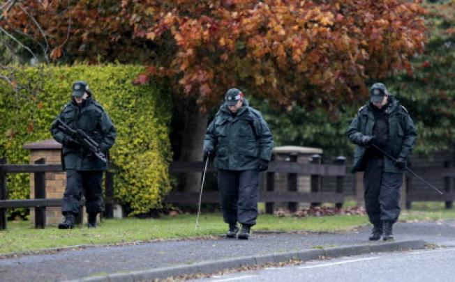 Northern Ireland police officers search the area close to a fatal shooting of a prison officer near Lurgan. An Irish nationalist has been arrested in connection with the shooting. Photo: AP 