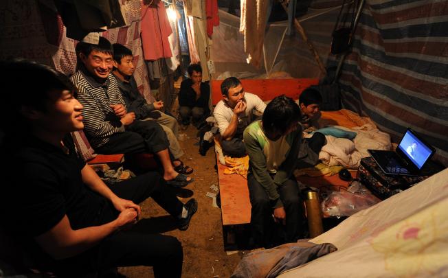 Migrant workers watching a video on a laptop under a self-built shelter shared with several hundred others in Hefei, central China's Anhui province. Photo: AFP
