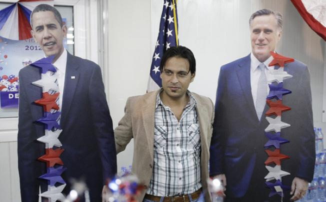 An Afghan man poses next to cutout figures of President Barack Obama (left) and Mitt Romney at the US Embassy in Kabul on Wednesday. Photo: AP