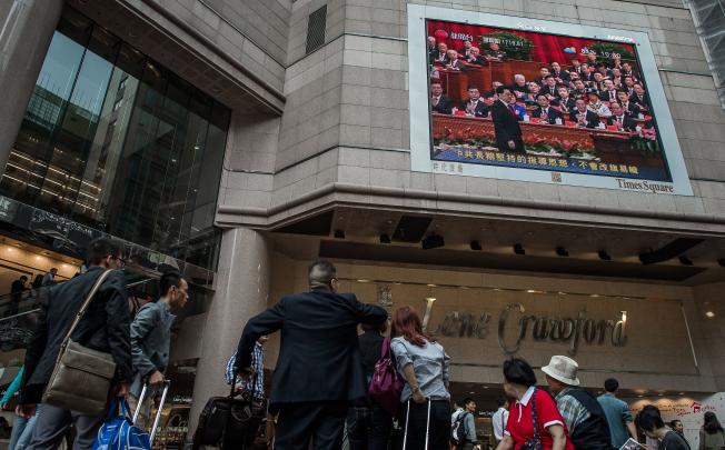People watch a large screen showing a news broadcast recorded in Beijing during the opening of the 18th Communist Party Congress, in Hong Kong on November 8, 2012. Photo: AFP