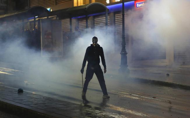 An armed protester in a cloud of tear gas in Athens' Syntagma Square during Wednesday night's violent protests. Photo: Reuters