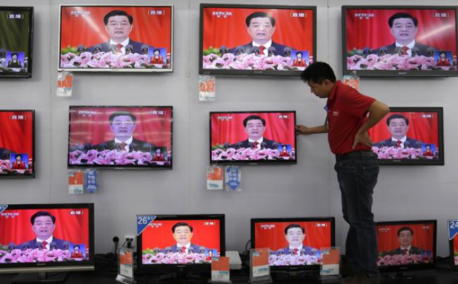 A man adjusts a television screen showing a live broadcast of Chinese president Hu Jintao speaking at the opening of the 18th Communist Party Congress. Photo: AFP