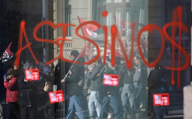 Graffiti sprayed on the front of a bank in Madrid says "murderers" in Spanish. Photo: AFP