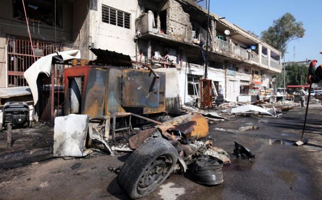 Damaged shops and cars are seen at the scene of a car bomb attack in Baghdad, on Wednesday. Photo: EPA