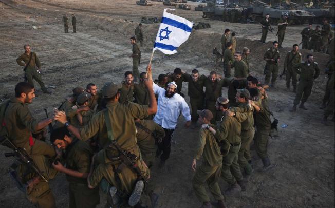 A Hasidic Jewish man dances with Israeli troops during a visit to support the soldiers near the border with the Gaza Strip. Photo: Reuters