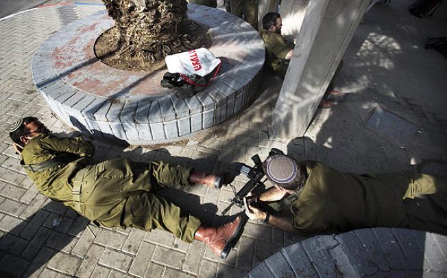 Israeli soldiers take cover during a rocket attack from the Gaza Strip in Yad Mordechay, southern Israel. Photo: AFP