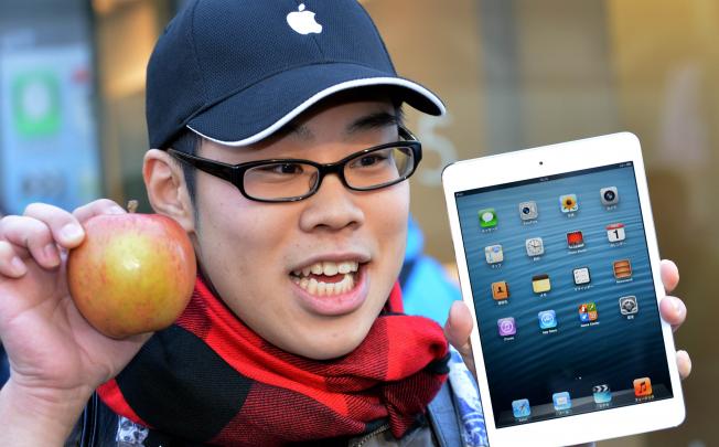 A customer holds up an apple as he purchases Apple's new 7-inch sized "iPad mini" tablet at an Apple store in Tokyo on November 2, 2012. Photo: AFP