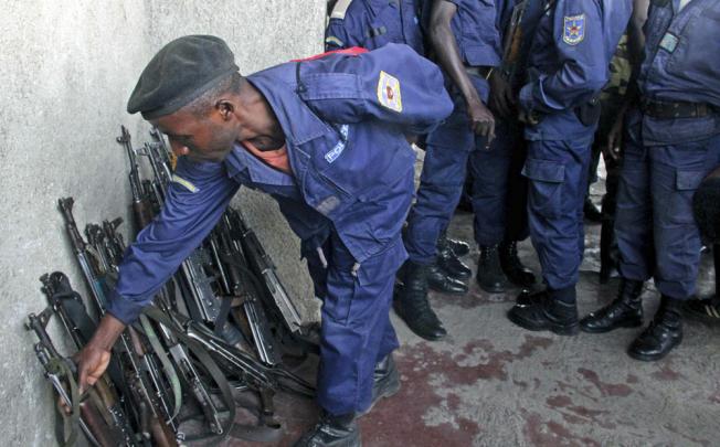 A Congo government policeman hands in his weapon to M23 rebels in Goma, Congo. Photo: AP