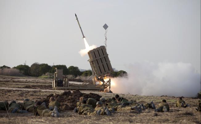 Israeli soldiers lie on the ground as an Iron Dome interceptor missile is launched near the city of Ashdod, Israel. Photo: AP