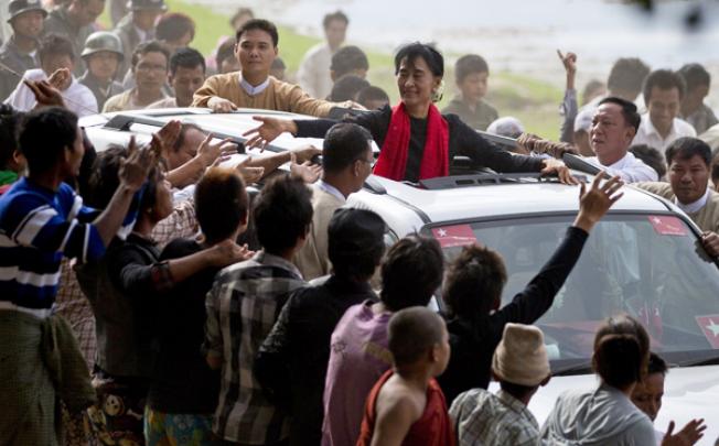 Supporters of opposition leader Aung San Suu Kyi reach to touch her hand as she leaves after a public meeting close to Letpadaung mine in Monywa on Friday. Photo: AP