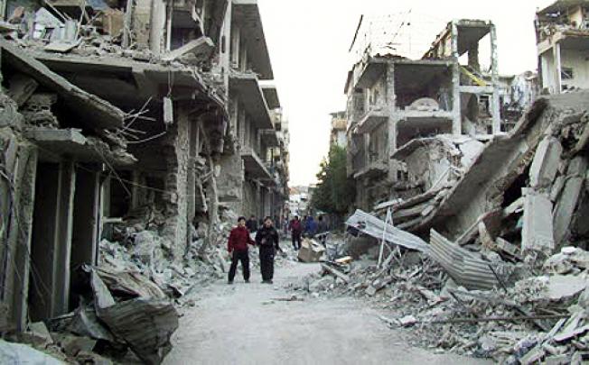 Syrian citizens walk through in a destroyed street as fighting continues to rage. On Thursday, Syrian troops mounted an assault on rebels near Damascus. Photo: AP