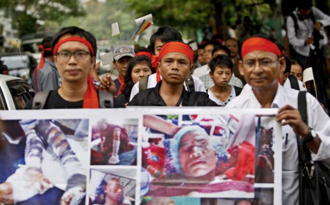 Demonstrators hold posters and Buddhist flags as they march during a protest against Myanmar authorities' violence on monks and villagers of the Monywa copper mine project. Photo: EPA