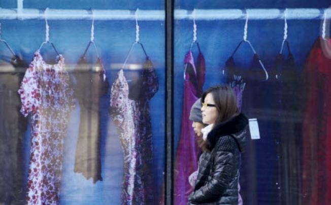 Two Chinese women make their way past a clothing shop in Beijing on November 29, 2012. Photo: AFP