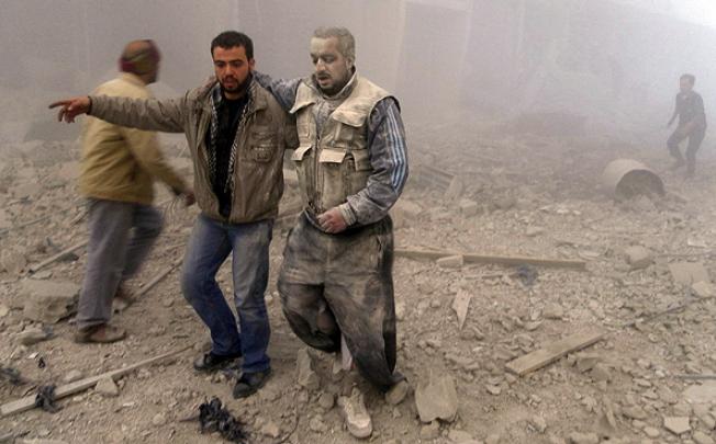 Rebel fighters emerge from buildings hitd by Syrian Air Force fighters in Akraba, Damascus. Photo: Reuters