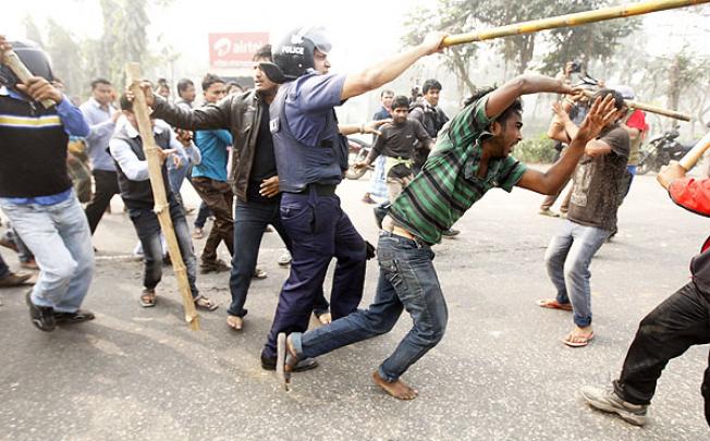 An opposition activist tries to escape as the police and pro-government activists beat him during countrywide road block protests in Bangladesh on Sunday. Photo: EPA
