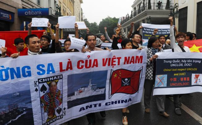 Protestors shout anti-China slogans and hold banners as they march towards the Chinese embassy in central Hanoi on Sunday. Photo: AFP