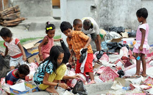 East Timorese children collect recycle items in Dili on Monday. The UN winds up its peacekeeping mission on Monday after 13 years East Timor. Photo: AFP